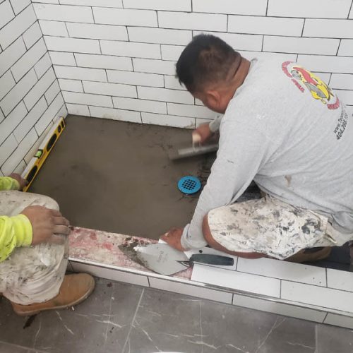 a man putting cement in a bathroom floor