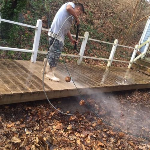 a man pressure washing a deck walkway