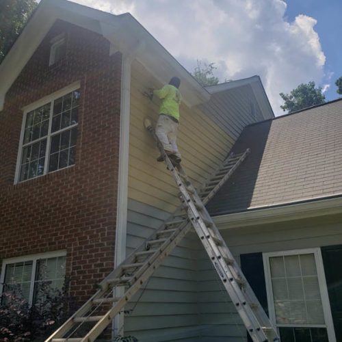 A person climbing on a ladder to paint a house